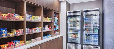 A snack and beverage vending area with multiple shelves stocked with various snacks and two beverage dispensers.