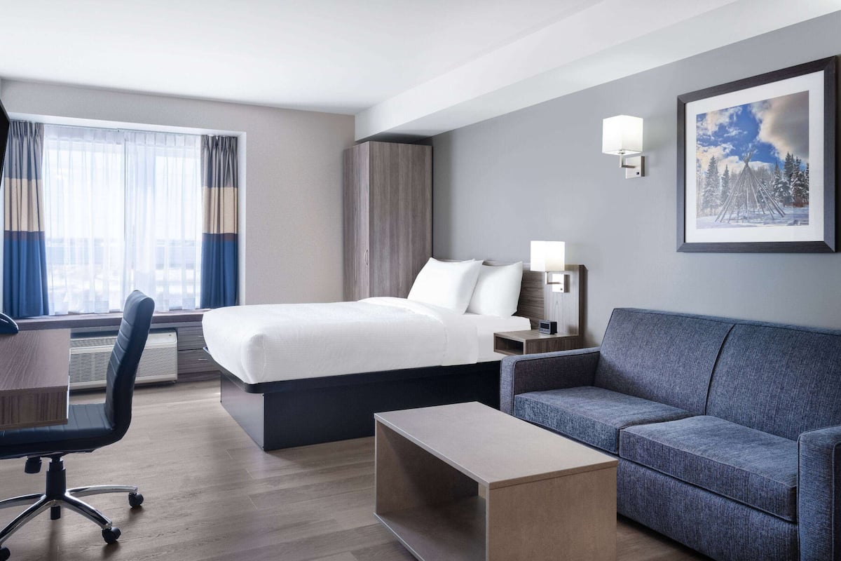 Une chambre d’hôtel moderne équipée d’un lit, d’un canapé, d’un bureau et d’une chaise.