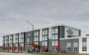 A modern Microtel hotel with a 'OPEN' sign, featuring a two-story structure with a grey and white color scheme, and a covered outdoor seating area. - Microtel Inn & Suites by Wyndham Kanata Ottawa West (Ottawa)