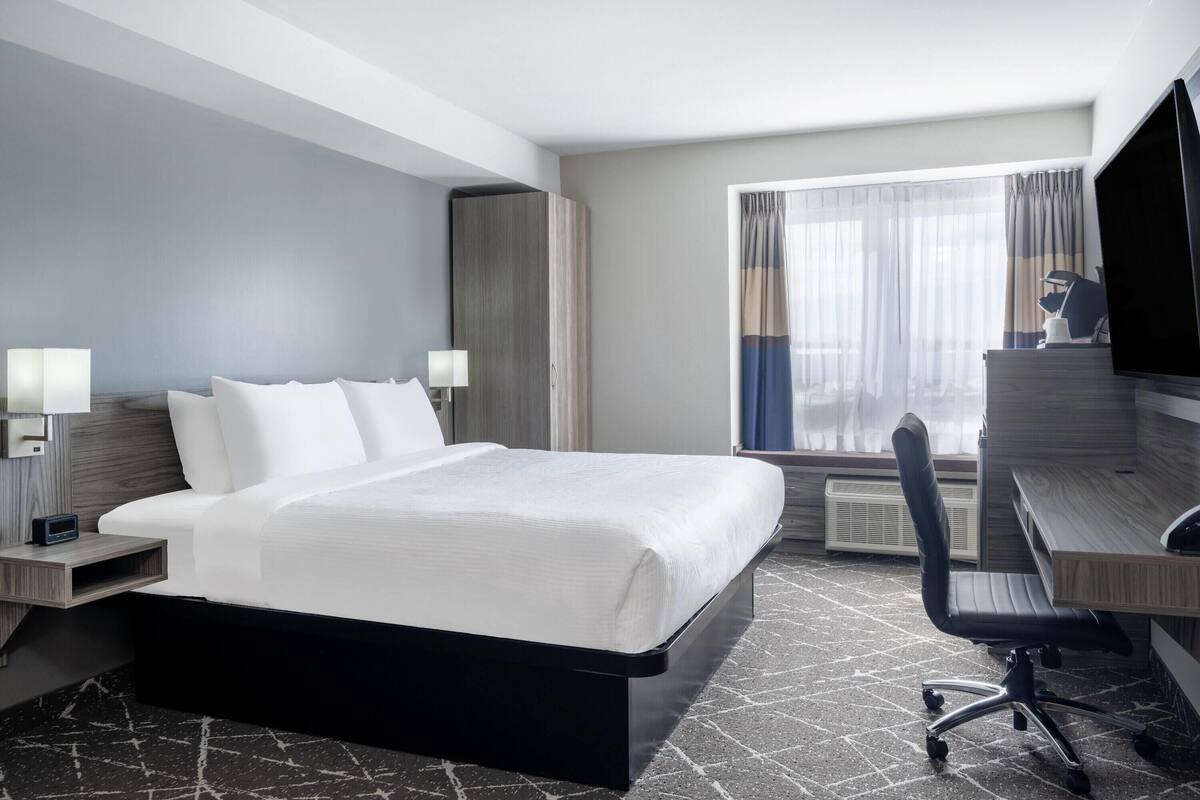 Une chambre d’hôtel avec un grand lit, un bureau, une chaise et un téléviseur.