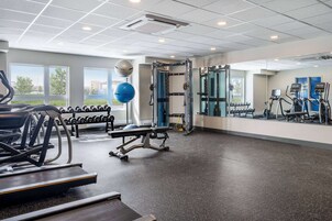 Un gimnasio con cintas de correr, pesas y equipo de ejercicio.