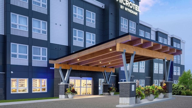 Un microhotel moderno con entrada cubierta, amplias ventanas y zona de estar al aire libre.