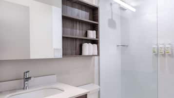 Ein modernes Badezimmer mit integriertem Waschbecken, einer Glasdusche und Holzregalen über dem Waschbecken.