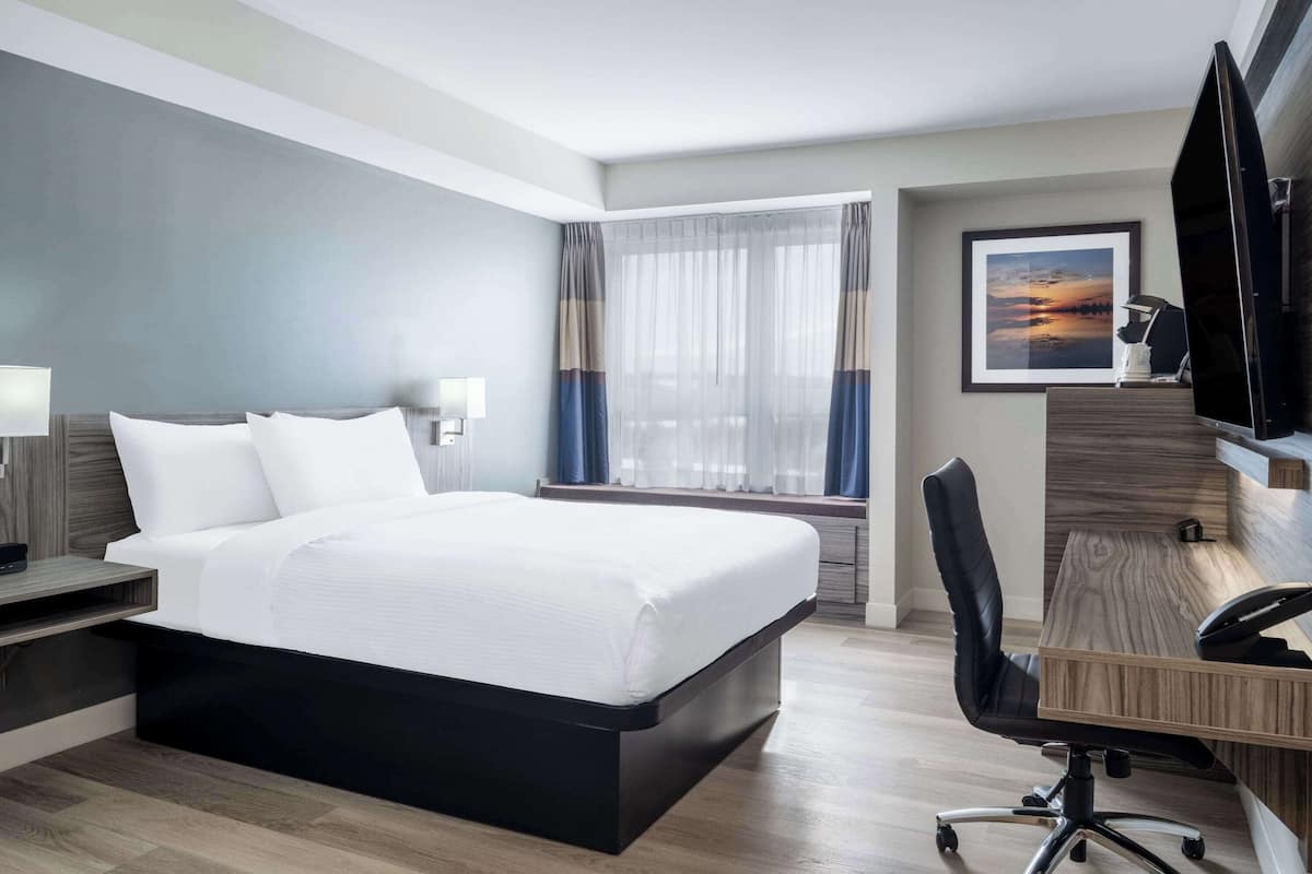 Une chambre d’hôtel moderne, dotée d’un grand lit, d’un bureau et d’une télévision.