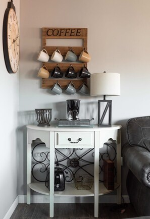 A white console table with a coffee station, a clock, and a coffee sign. - Incredible Mt. LeConte Views/Indoor Pool & Hot Tub (Gatlinburg)