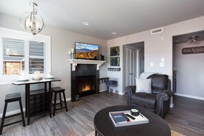 A living room with a fireplace, a television, a dining area with a table and chairs, and a leather armchair. - Incredible Mt. LeConte Views/Indoor Pool & Hot Tub (Gatlinburg)