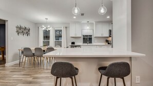 Une cuisine moderne avec des armoires blanches, un grand îlot central et des luminaires suspendus.