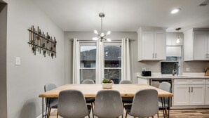 Une cuisine moderne avec des meubles blancs, une table à manger en bois et des chaises grises.