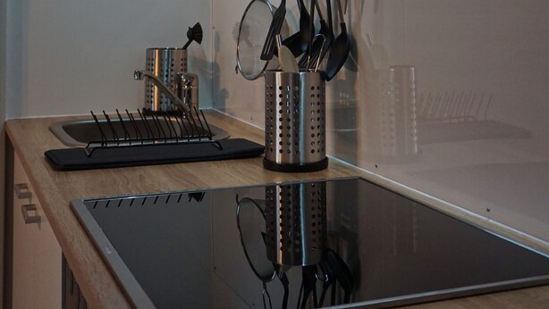 Una cocina moderna con estufa de acero inoxidable, un colgador para ollas y un horno empotrado.