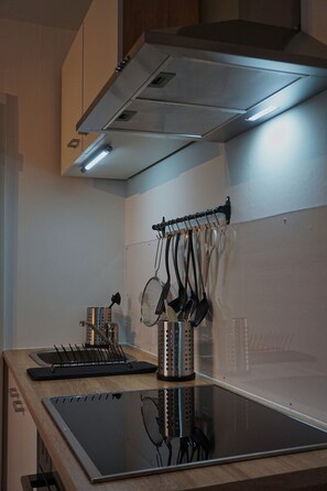 Une cuisine moderne dotée d’une cuisinière en acier inoxydable, d’un porte-ustensiles suspendu et d’un four encastré.