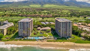 A coastal resort with multiple high-rise buildings, a beachfront, and a golf course in the background.