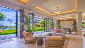 A spacious living area with a large glass door leading to a pool, a sofa, a coffee table, and a dining area with chairs.