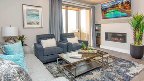A modern living room with a fireplace, a large window with curtains, and a flat-screen TV on the wall. - Sage Creek Resort E1 * Heated Pools * 2 Hot Tubs (Moab)