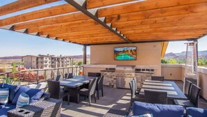 An outdoor patio with a wooden pergola, a barbecue grill, and a TV screen. - Sage Creek Resort E1 * Heated Pools * 2 Hot Tubs (Moab)