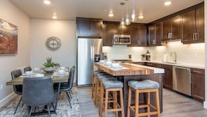 A modern kitchen with dark wood cabinets, stainless steel appliances, and a central island with bar stools. - Sage Creek Resort E1 * Heated Pools * 2 Hot Tubs (Moab)