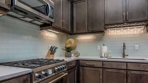 A kitchen with dark cabinets, stainless steel appliances, and a white countertop. - Sage Creek E3 *Pet Ok* Pvt Hot Tub * Heated Pools (Moab)