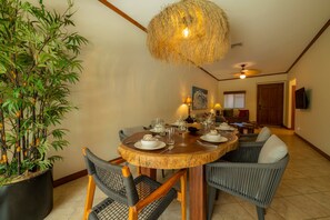 A dining area with a round wooden table, chairs, and a hanging light fixture.