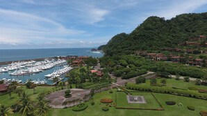 A marina with numerous yachts docked, surrounded by lush greenery and residential buildings. - Veranda 4F 2 bdr Garden View in Los Suenos (Playa Herradura)