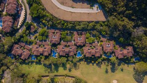 An aerial view of a residential area with multiple houses, a curved road, and a roundabout.
