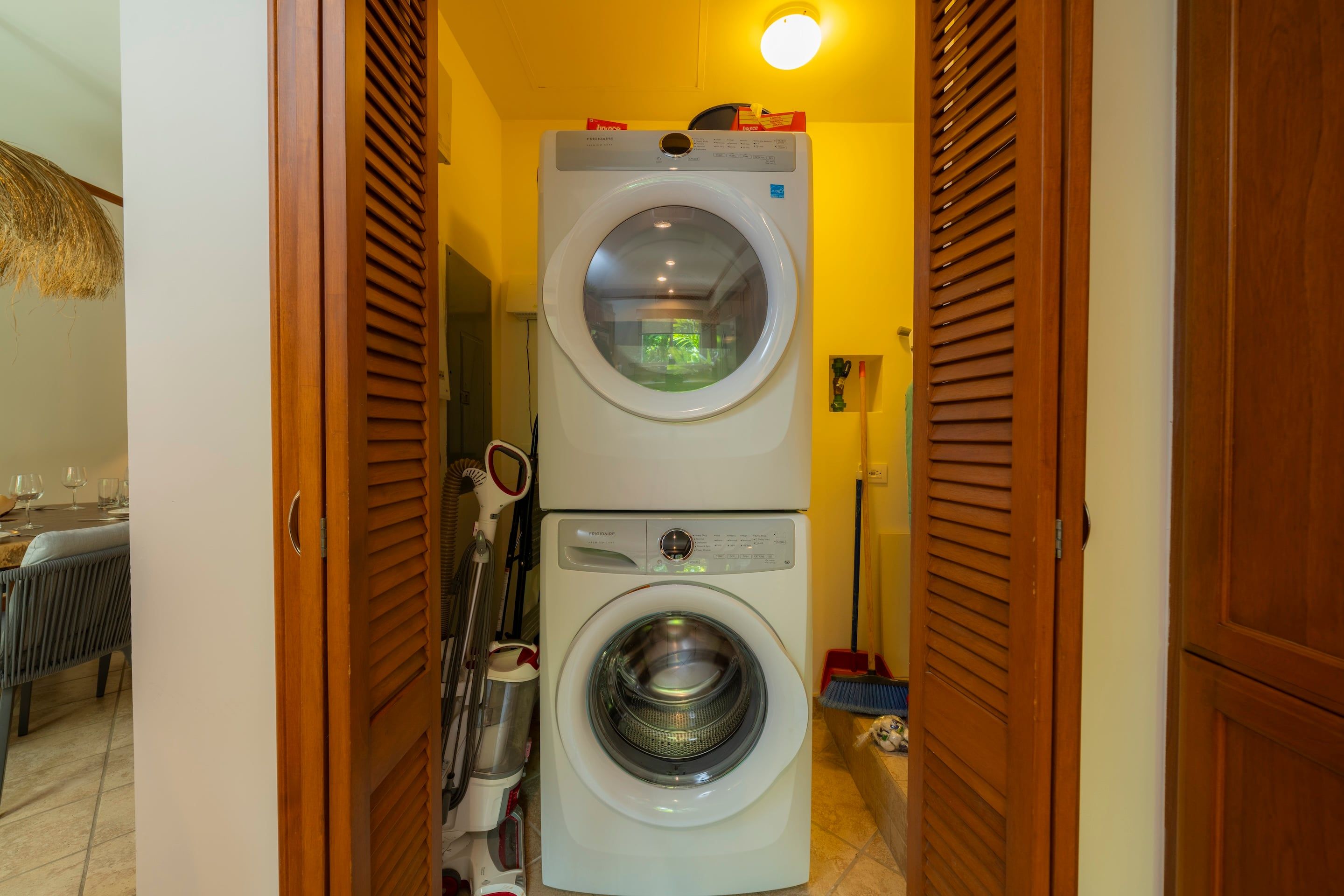 A laundry area with two stacked washing machines and a drying machine.