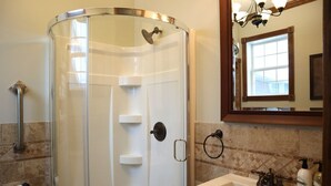 A bathroom with a glass shower enclosure, a white sink, a mirror, and a towel ring.