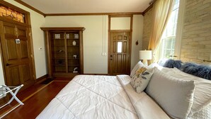 A bedroom with a large bed, wooden wardrobe, and a window with curtains.