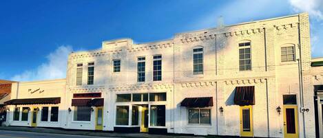 A white building with multiple storefronts, including a barber shop and a restaurant.