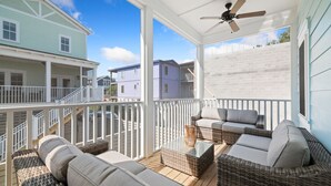 Una terraza techada al aire libre con muebles de mimbre y un ventilador de techo.