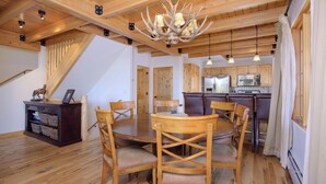Un comedor de madera con candelabro, sillas de madera y una mesa.