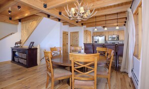 A wooden dining area with a chandelier, wooden chairs, and a table.