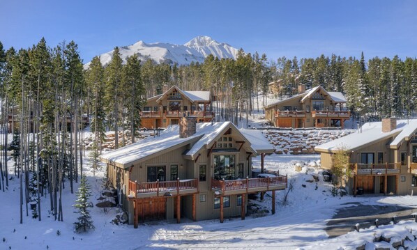A lodge with multiple cabins, wooden balconies, and a snowy forest backdrop.