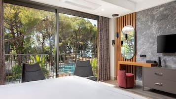Camera d'albergo moderna con una grande finestra, un letto, una TV e una scrivania in legno.