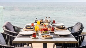 Una mesa lista para el desayuno, con vistas al mar y a las montañas.