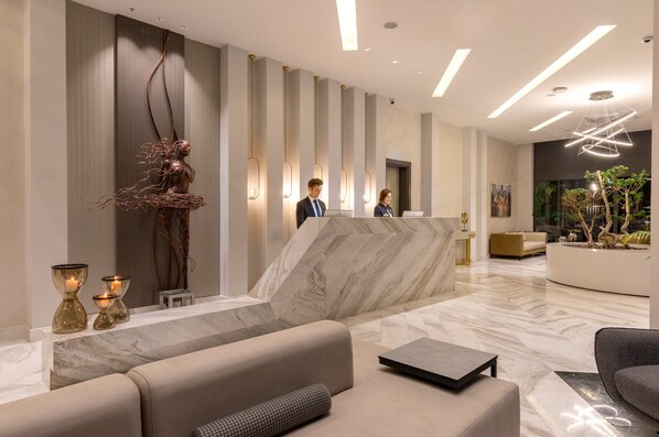 Un vestíbulo moderno con mostrador de recepción, zona de estar y vistas a plantas de interior.