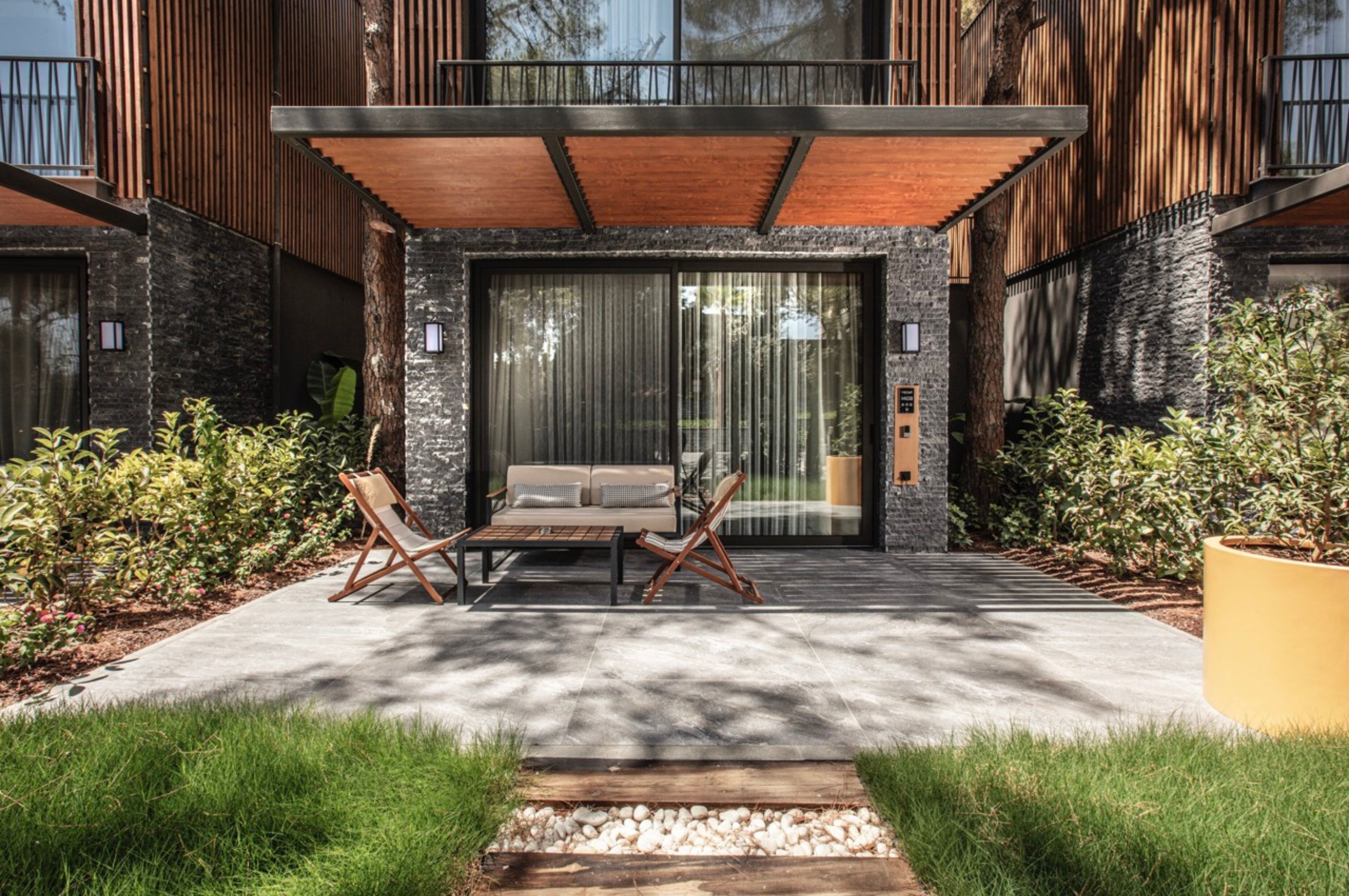 Une maison moderne dotée d’un patio, d’un espace salon extérieur et d’une grande fenêtre.