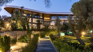 A modern building with a curved facade, multiple balconies, and a landscaped garden with a pathway. - Unique Life Style Hotel (Kusadasi)
