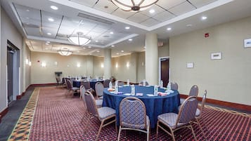 A conference room with round tables, chairs, and a carpeted floor.