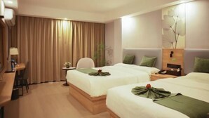 A hotel room with two beds, a desk, a chair, a small table, and a wall-mounted TV. - GreenTree Inn Express Hotel (Haikou Haixiu Middle Road Bangbaihui City Branch) (Haikou)