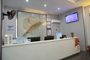 Mostrador de recepción con separador de vidrio, televisor montado y extintor.