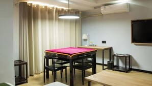 A room with a dining table, chairs, a small desk, a lamp, and an air conditioning unit. - GreenTree Inn Express Hotel (Haikou Haixiu Middle Road Bangbaihui City Branch) (Haikou)