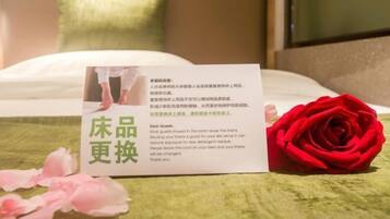 Una habitación de hotel con una cama, una rosa roja y una tarjeta sobre la cama.