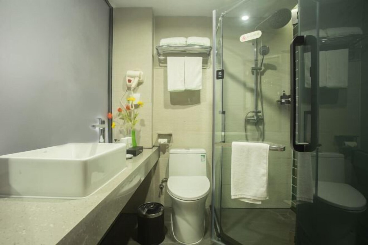 A modern bathroom with a glass-enclosed shower, a white sink, and a toilet.