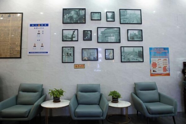 A waiting area with four chairs, two small tables, and a wall adorned with framed photographs.