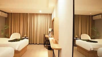 A hotel room with two beds, a desk, and a mirror.