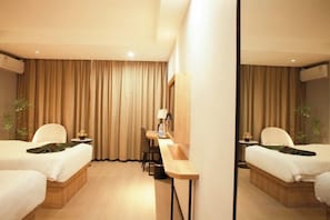 A hotel room with two beds, a desk, and a mirror.