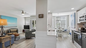 A modern kitchen with a central island, a dining area with a table and chairs, and a living room with a sofa and a TV. - Cozy 1BR Villa w/ Lagoon Views (Hilton Head Island)