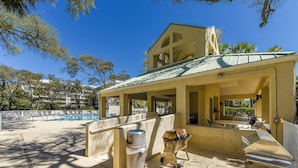 A covered outdoor area with a pool, lounge chairs, and barbecue equipment. - Cozy 1BR Villa w/ Lagoon Views (Hilton Head Island)