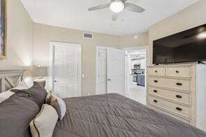 A bedroom with a bed, a dresser, a television, and a ceiling fan.