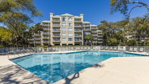 Un hôtel doté d’une piscine, de plusieurs balcons et entouré d’arbres.