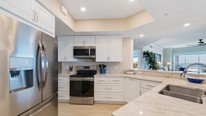 A modern kitchen with stainless steel appliances, white cabinetry, and a large island with a sink. - Direct Ocean Front Villa w/ Large Balcony (Hilton Head Island)